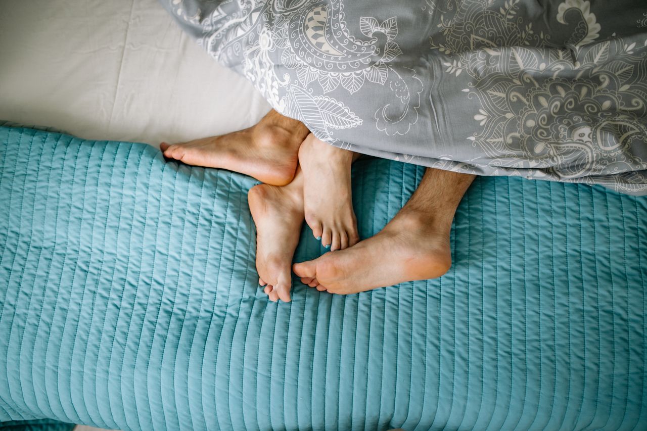 Intimate top view of a cozy couple cuddling in bed, highlighting love and togetherness.