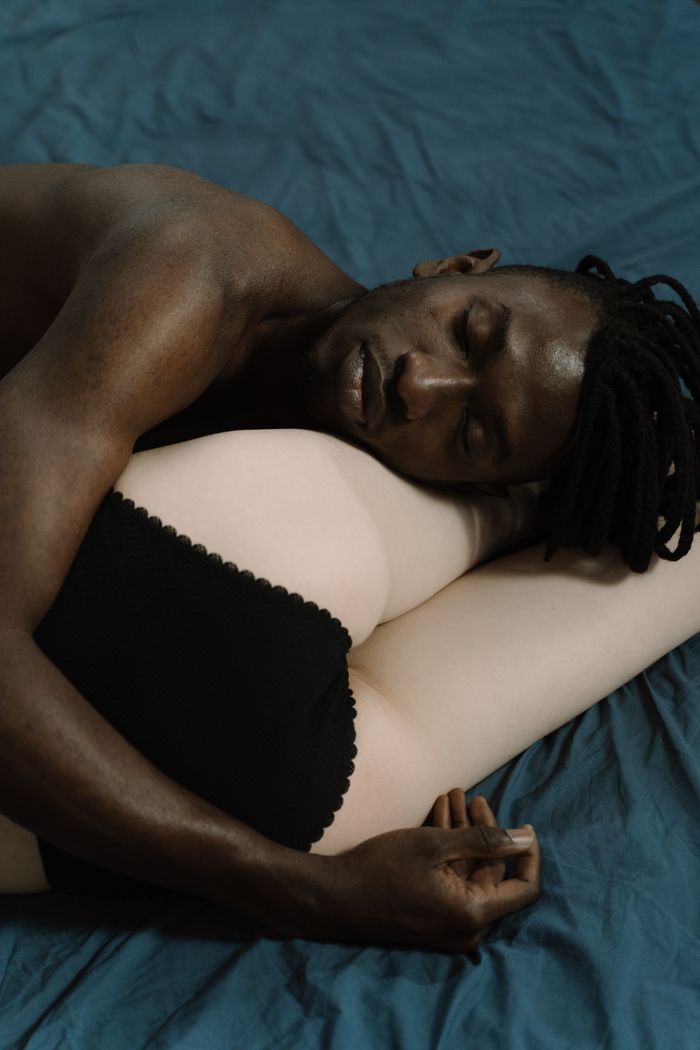 A tender moment of an interracial couple embracing while asleep on a bed.