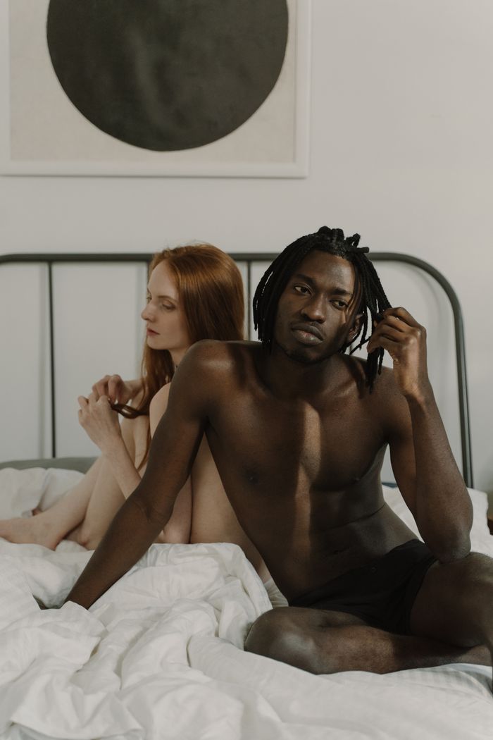 A romantic scene of a shirtless interracial couple on a bed, showcasing intimacy and togetherness.